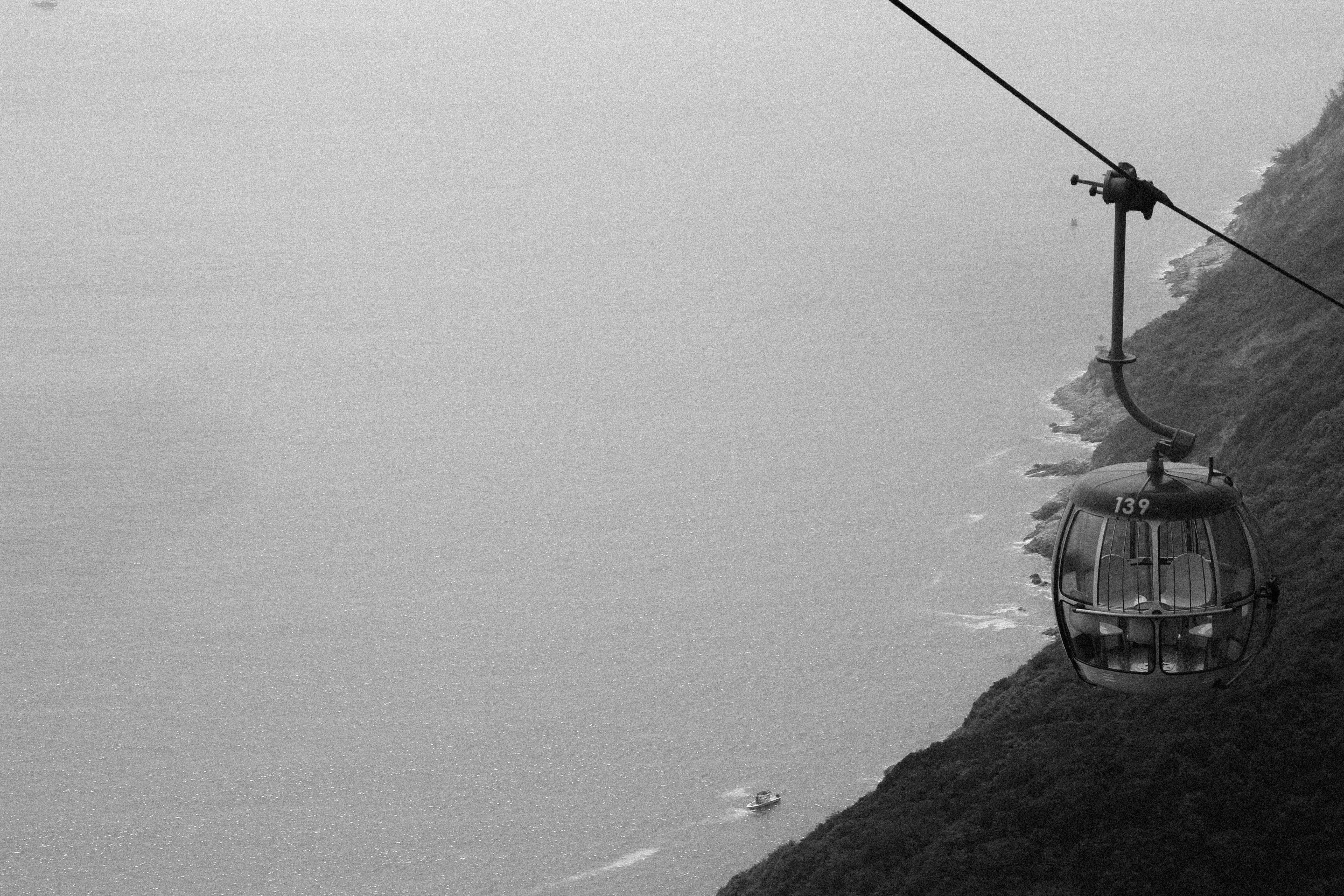 grayscale photography of cable car distance with sea